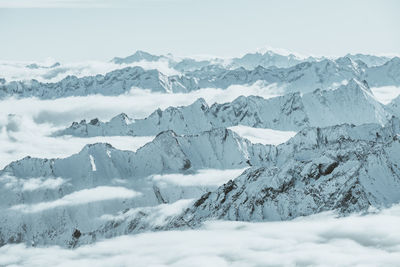 Layers of snow covered mountains above the clouds in tyrol, austria