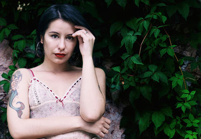 Portrait of beautiful young woman against plants