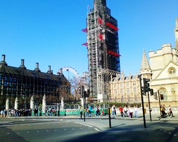 Group of people in front of buildings against blue sky