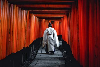 Rear view of man walking in temple outside building