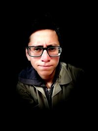 Portrait of man wearing eyeglasses against black background