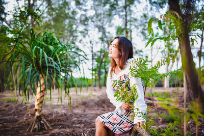 Young woman standing against plants