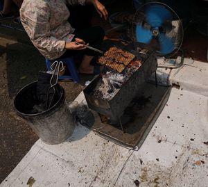 Low section of person cooking food on barbecue grill