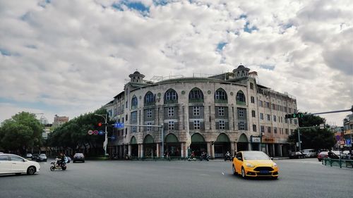 Vehicles on road against cloudy sky