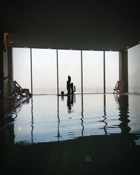 Silhouette people sitting by swimming pool