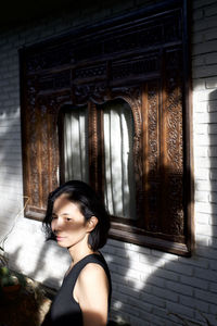 Portrait of woman standing against wall