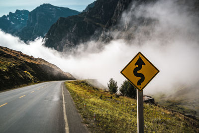 Sign on country road against mountains in foggy weather