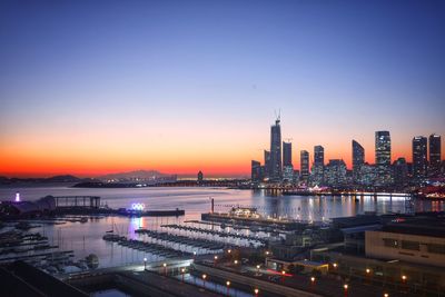 Illuminated buildings in city against sky during sunset
