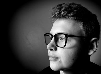 Portrait of young man with eyeglasses against wall