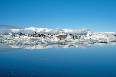 Scenic view of frozen lake against blue sky