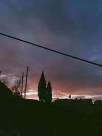Low angle view of silhouette electricity pylon against sky during sunset