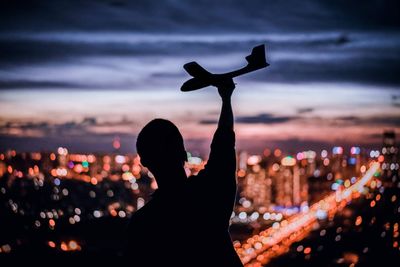 Silhouette person against illuminated city at night