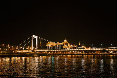 Illuminated bridge over river against sky at night