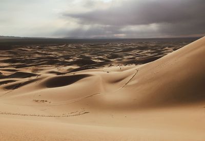 Scenic view of sand dune on beach against sky