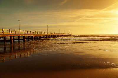 Pier over sea against sky during sunset