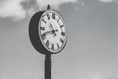 Low angle view of clock against sky