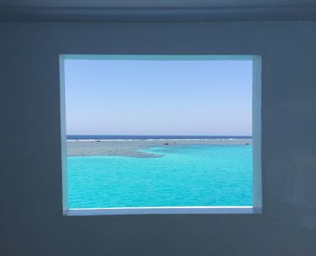 Scenic view of sea against blue sky seen through window