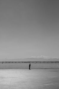 Man standing on shore against clear sky
