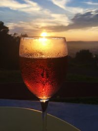 Close-up of drinking glass against sunset