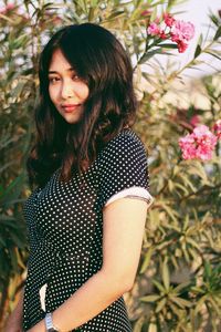 Portrait of woman standing against tree