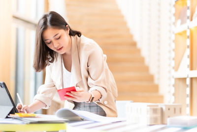 Young woman using phone while sitting on table