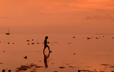 Full length of boy walking on beach during sunset