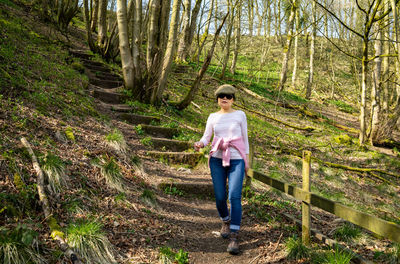 A vietnamese woman walks down a steep forest path in the peak district, uk