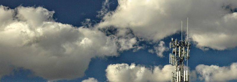 Low angle view of crane against cloudy sky