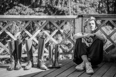 Man sitting near a fence next to vintage boots 