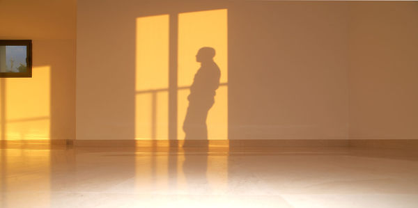 Silhouette man standing against wall