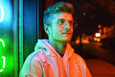 Close-up of young man wearing eyeglasses at night