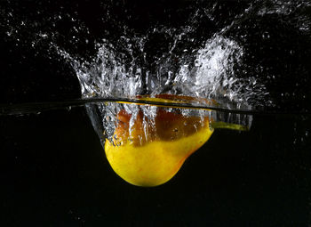 Close-up of water splashing on glass against black background