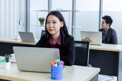 Young woman using mobile phone while sitting on table