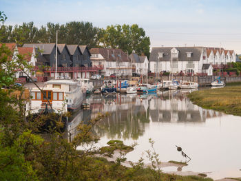 Boats moored in river against houses in town