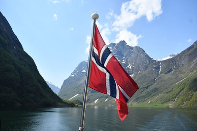 Red flag by lake against sky