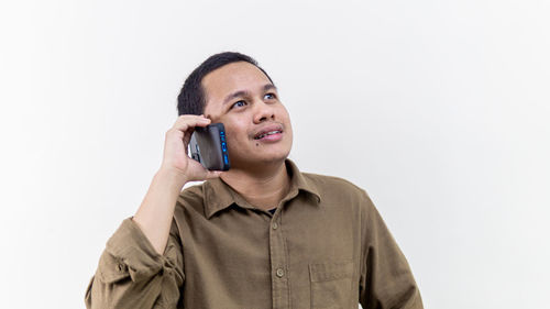 Mid adult man looking away while standing against white background