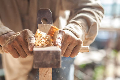 Midsection of carpenter using plane on wood