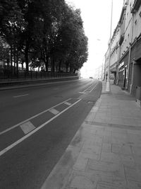 Empty road along trees and buildings
