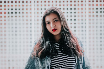 Portrait of young woman standing against wall