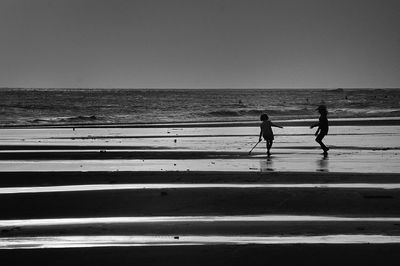 People walking on beach against clear sky