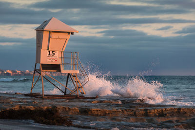 Lifeguard hut on beach against sky during sunset