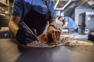 Male chef writing with marker on baking paper while cooking food in restaurant kitchen