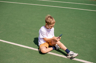 A boy on the street writes a text message on his phone