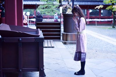 Full length of woman praying at temple