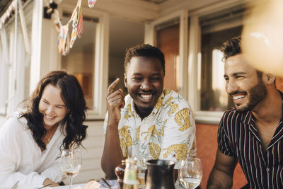 Cheerful friends having fun at dining table during dinner party