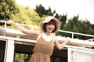 Portrait of smiling woman standing against railing