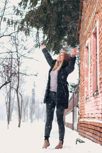 Full length of woman standing on snow covered tree