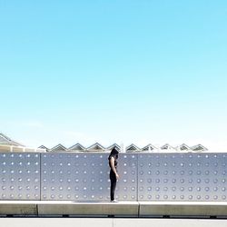 Low angle view of man standing against clear blue sky