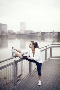 Young woman stretching on railing