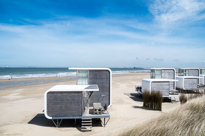 Deck chairs on beach against sky